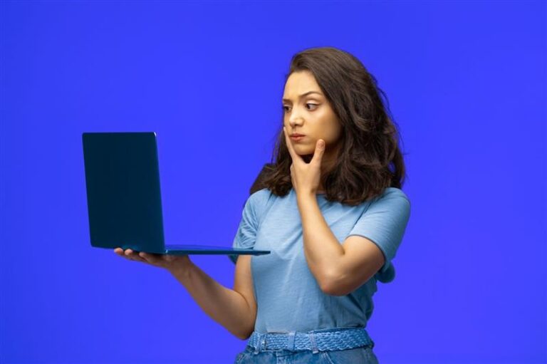 Pessoa olhando para o notebook com expressão pensativa, representando a escolha de uma plataforma de vendas para negócios digitais.