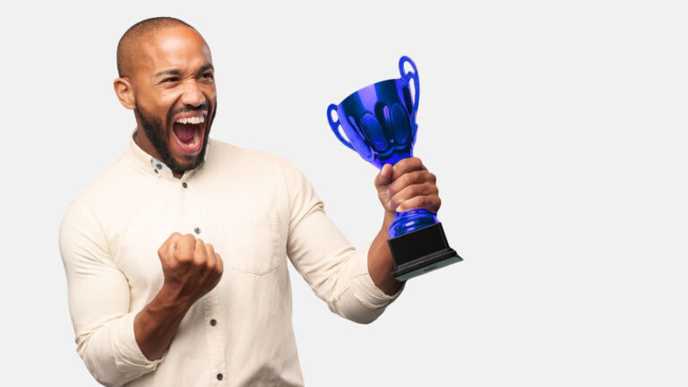 Pessoa comemorando com um troféu azul nas mãos, expressando entusiasmo e vitória.